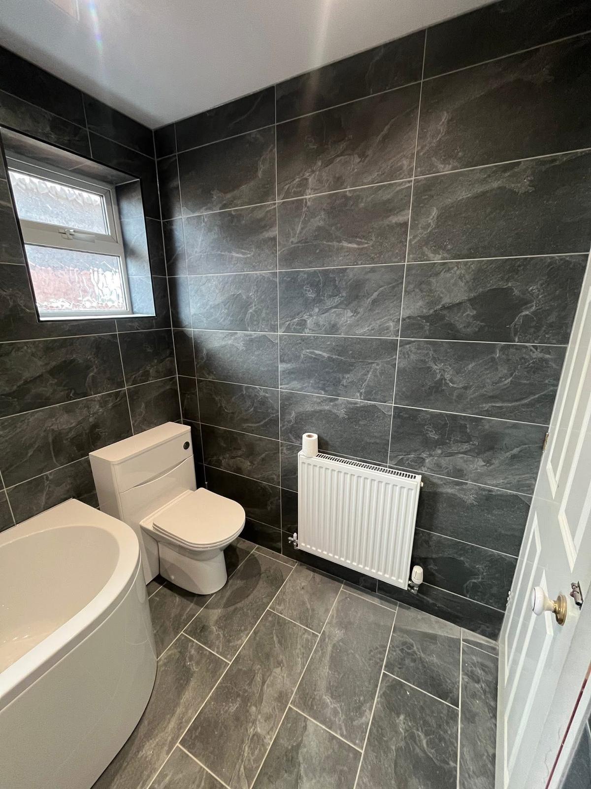 Slate-tiled bathroom refit with corner bath and radiator, North Lincolnshire