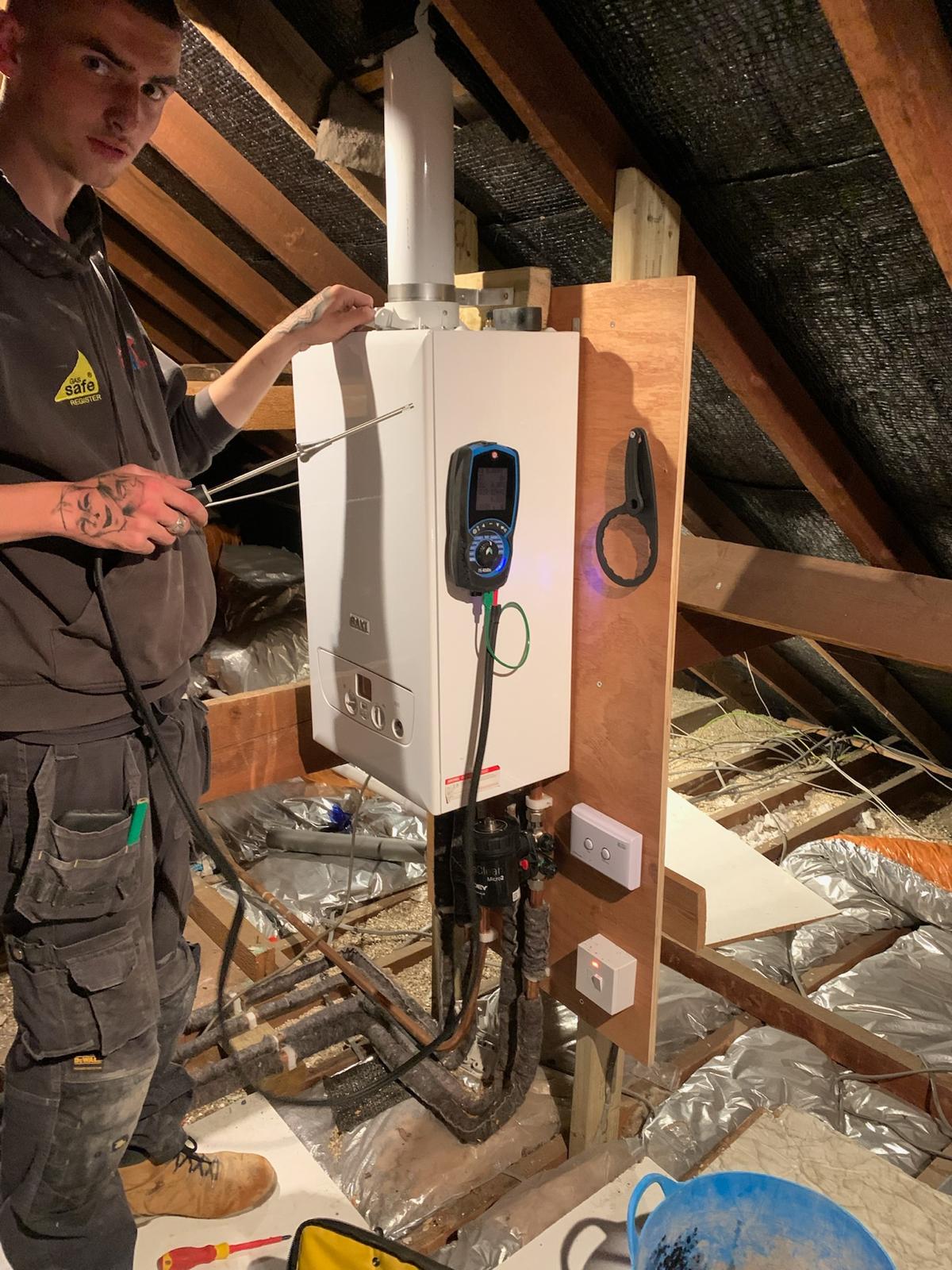 Gas Safe engineer commissioning loft boiler with flue gas analyser