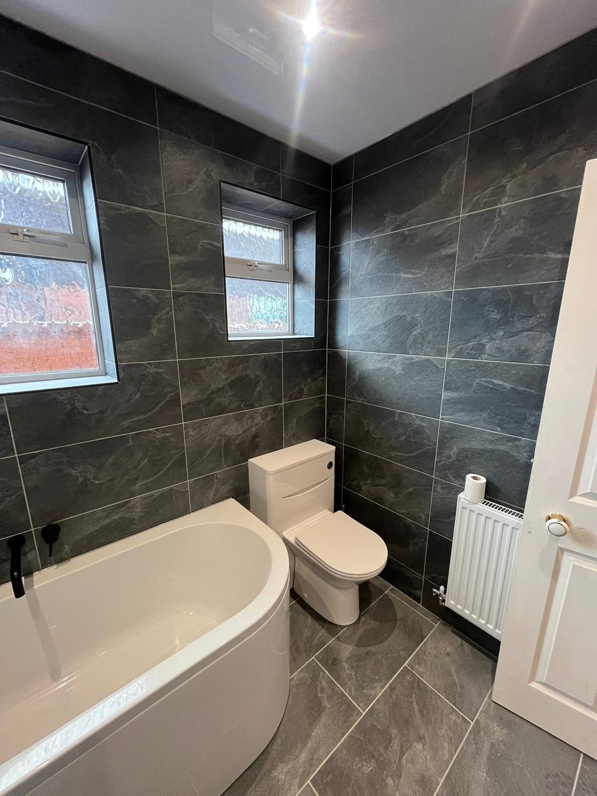 Finished bathroom installation with slate tiling and bath